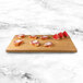 A rectangular faux bamboo melamine display riser with sliced watermelon and bread on it.