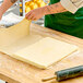 A person rolling out Echire unsalted butter sheet on a wooden surface.