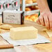 A person cutting up a block of Le Gall Salted Brittany Butter on a table.