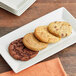 A stack of white plates with Red Plate Foods Individually Wrapped Vegan Cookies on top.