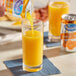 A hand pouring Ocean Spray Orange Juice Blend from a can into a glass.