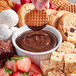 A bowl of Lyons Fountain Supreme chocolate sauce with a cookie dipped in it.