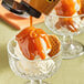 A glass bowl of Lyons Old Fashioned Caramel Hot Fudge Topping on a bowl of ice cream.