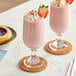 Two glasses of pink Maui by Lyons strawberry smoothies with strawberries on top.