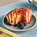 A piece of cake with Lyons Blackberry Flavoring Sauce and berries on a plate.