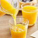 A glass pitcher pouring Ocean Spray Orange Juice into a cup.