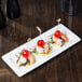 A Libbey white rectangular porcelain plate with shrimp and tomatoes on it.