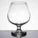 A Libbey brandy glass with a clear liquid on a table.