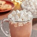 A glass mug of hot chocolate with Campfire Mini White Marshmallows on top.
