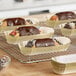 A tray of pastries in gold oval baking cups on a rack.