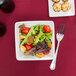 A bowl of salad with tomatoes, lettuce, and croutons on a table.