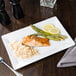 A Libbey Ultra Bright White rectangular porcelain plate with asparagus, salmon, and rice on a table.
