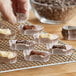 A hand holding a tray of brown oval baking cups filled with chocolate candy.