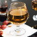 A close up of a Libbey brandy glass filled with liquid on a table