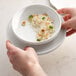 A person holding a Libbey white porcelain bowl of rice.