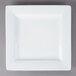 A Libbey Ultra Bright White square porcelain plate with a wide rim on a gray surface.