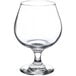 A Libbey brandy glass with a small amount of liquid on a white background.