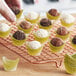A hand placing chocolate truffles in a yellow and white Novacart boat baking cup.