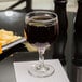 A Libbey red wine glass filled with red wine on a table.