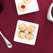 A Libbey Ultra Bright White Coupe Square Porcelain Plate with cookies and coffee on it.