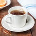 A Libbey round cream porcelain saucer with a cup of tea on it, with orange slices.