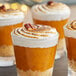 Glasses of desserts topped with whipped cream and nuts.