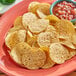 A plate of Clown Whole Grain round tortilla chips with a bowl of salsa.
