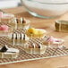 A rack of small desserts in Novacart gold oval baking cups.