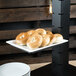 A Libbey white rectangular porcelain plate with bagels on a table.