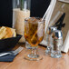 A Libbey goblet filled with brown liquid on a table.