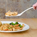 A hand using a Thunder Group Blue Bamboo melamine spatula to serve food on a plate.
