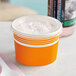 An orange Choice paper frozen yogurt cup with a flat lid.