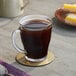 A glass cup of Maxwell House decaf coffee on a table.