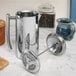 A Frieling USA stainless steel French press on a marble counter with a spoon.