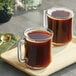 A wooden tray with two glass mugs of Maxwell House coffee.