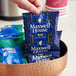 A hand holding a blue Maxwell House Master Blend coffee packet.