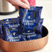 A hand holding a Maxwell House Original Roast coffee packet.
