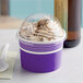 A purple Choice paper frozen yogurt cup with a dome lid filled with white and brown frozen yogurt.