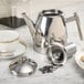 A silver Primo stainless steel tea pot on a marble counter.