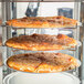 A pizza on a rack in a Hatco Flav-R-Fresh countertop pizza warmer.