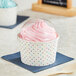 Two polka dot paper cups of frozen yogurt with dome lids on a table.