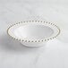 A white plastic bowl with gold beaded trim.