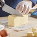 A person cutting a block of Cabot unsalted butter on a table.