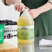 A person holding a green jug of yellow Noble Chemical Arctic Ice Machine Cleaner.