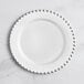 A Visions white plastic plate with silver beaded rim.