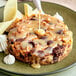A piece of cake drizzled with Monin White Chocolate Flavoring Sauce on a plate.