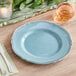 A Visions steel blue plastic plate with a silver vintage rim on a table with cutlery.