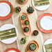 A table set with Visions white plastic plates with gold beaded rims and silver utensils.