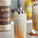 A glass of brown liquid with whipped cream and Monin Dark Chocolate sauce on top.