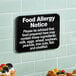 A black and white Lavex Food Allergy Notice sign on a wall.